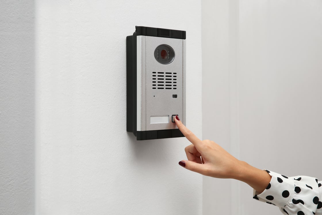 African-American Woman Ringing Intercom with Camera in Entryway,